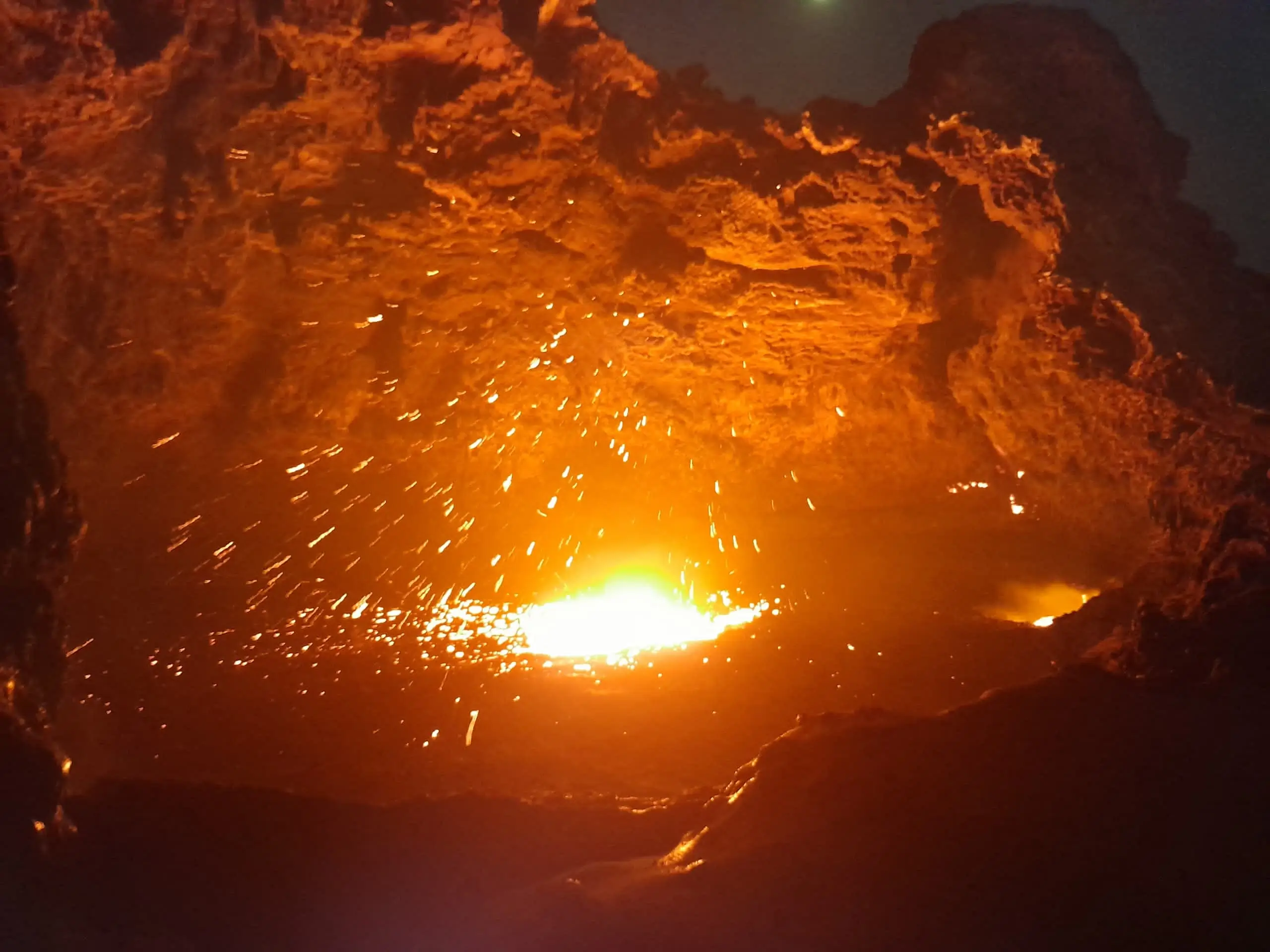 Molten lava sparks erupting from Erta Ale volcano at night, Ethiopia