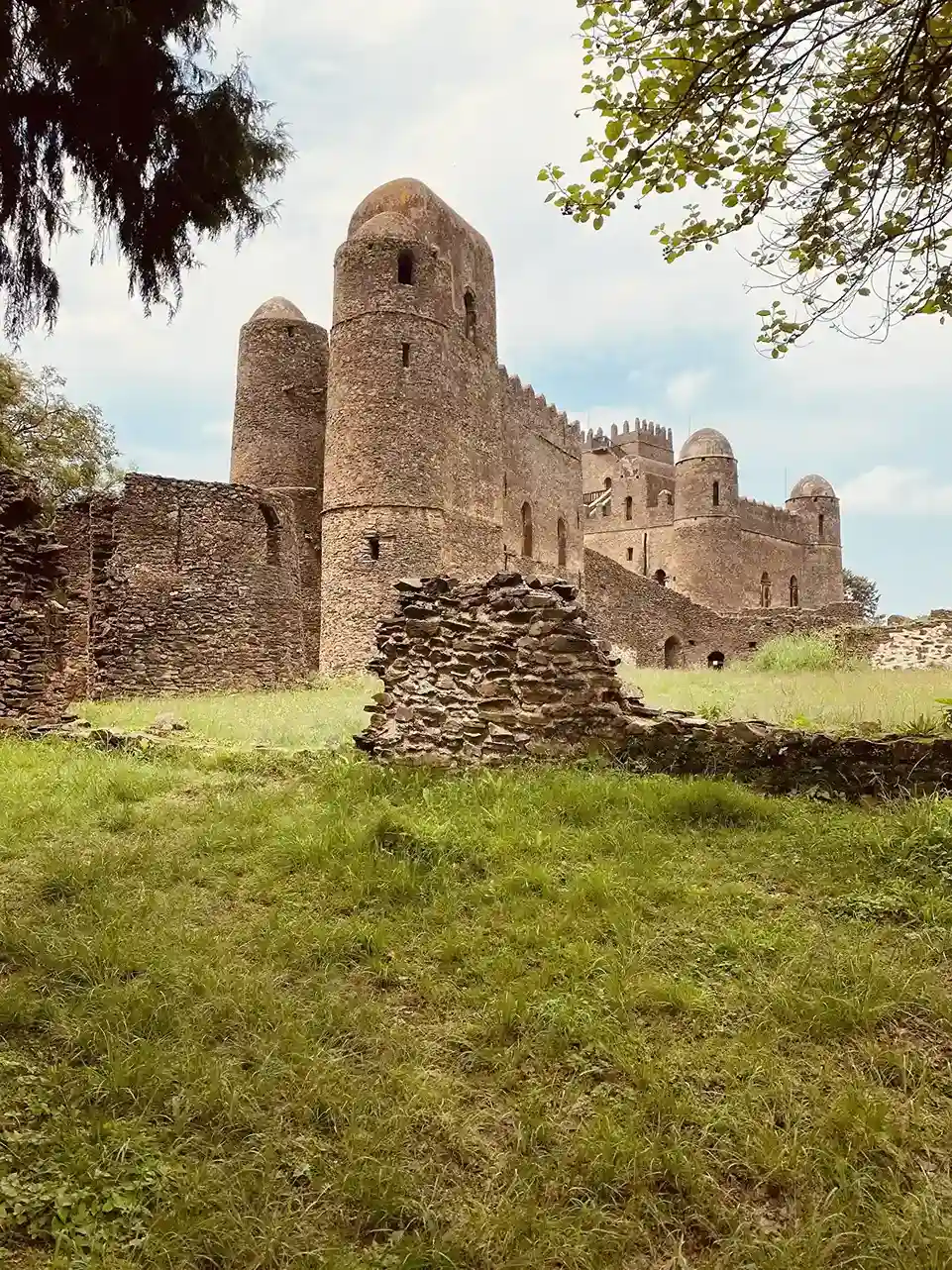 Stone castle turrets flying the Ethiopian flag in Gondar's Royal Enclosure