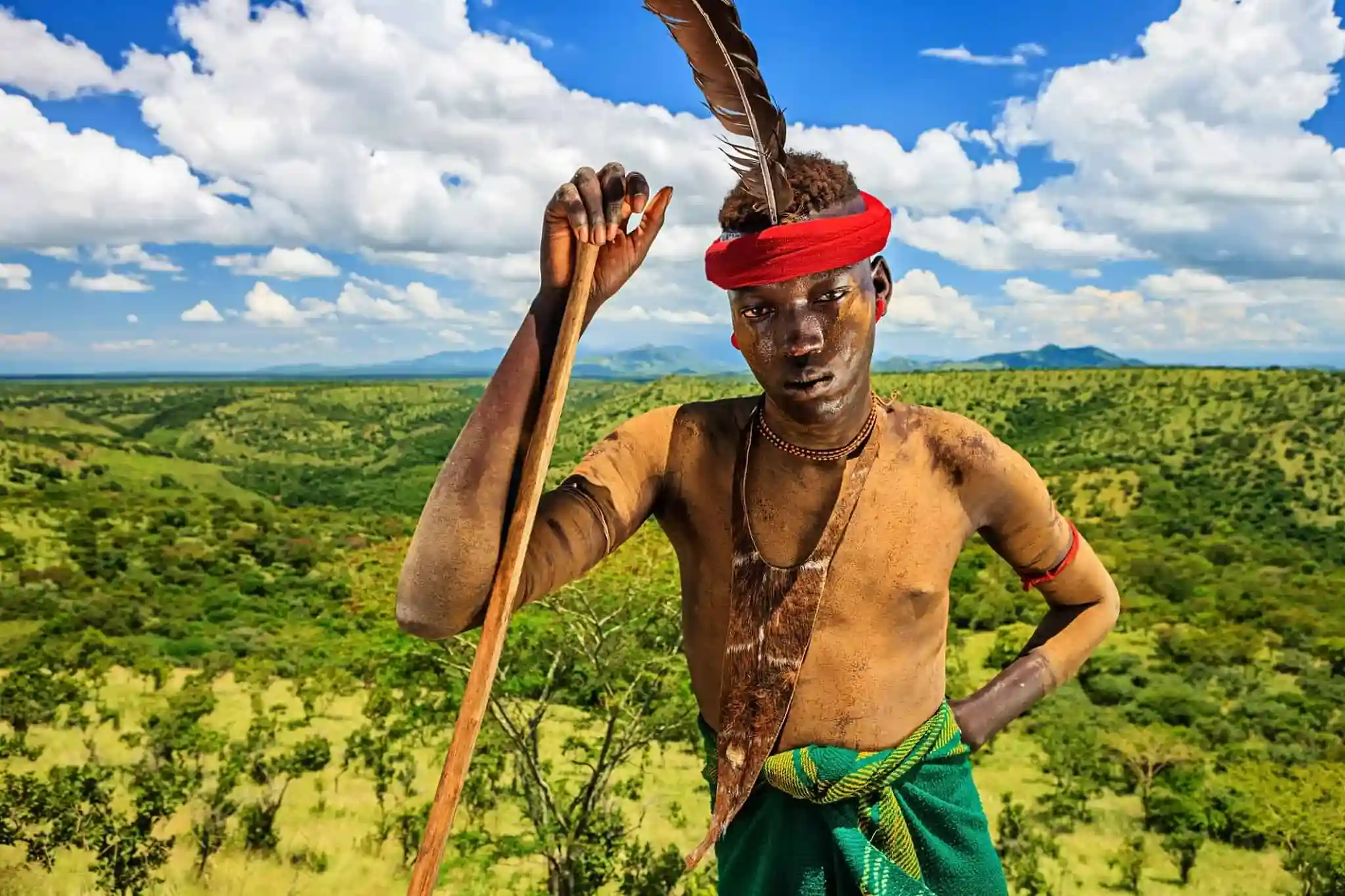 Tribal warrior overlooking the green hills of the Omo Valley, Ethiopia