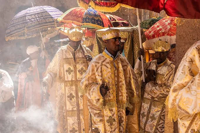 Ethiopian Orthodox priests in ornate robes carrying the Tabot under colorful umbrellas during Timkat