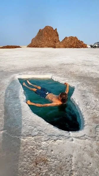 Traveler floating in a desert salt pool at Lake Asale, Danakil Depression, Ethiopia